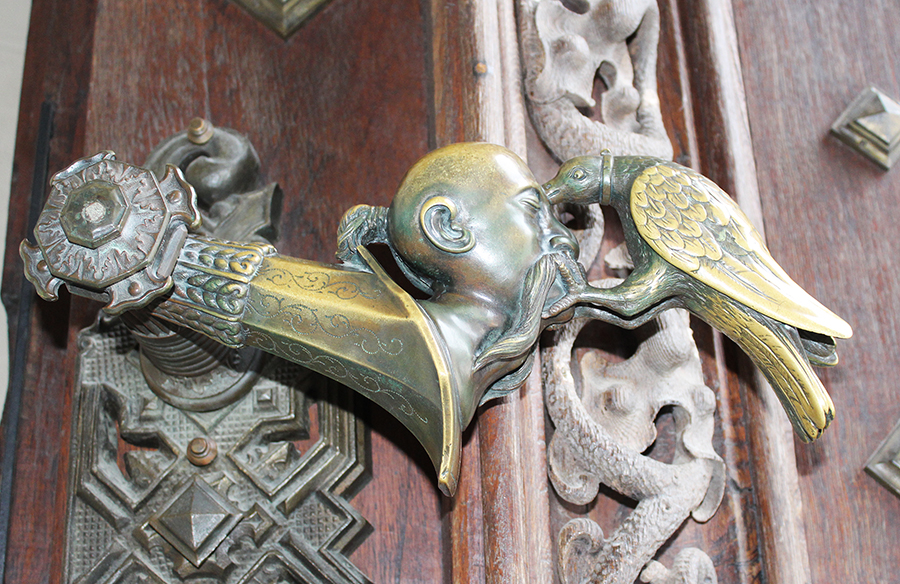 heraldická figurka krkavce klovajícího do hlavy Turka na klice hlavní brány